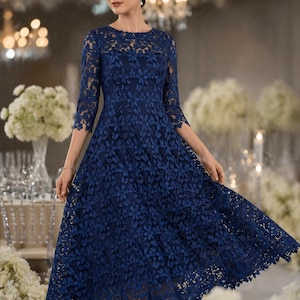 May include: A navy blue midi dress featuring three-quarter length sleeves and a round neckline. The garment is constructed from an intricate floral lace overlay that covers the bodice and the full, flared skirt, creating a textured appearance.