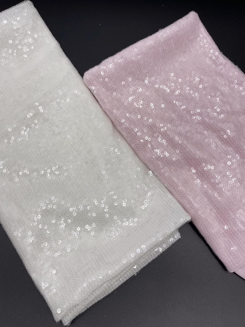 K&ouml;nnte beinhalten: Zwei Stoffst&uuml;cke mit Pailletten. Eines ist wei&szlig; und das andere ist rosa.