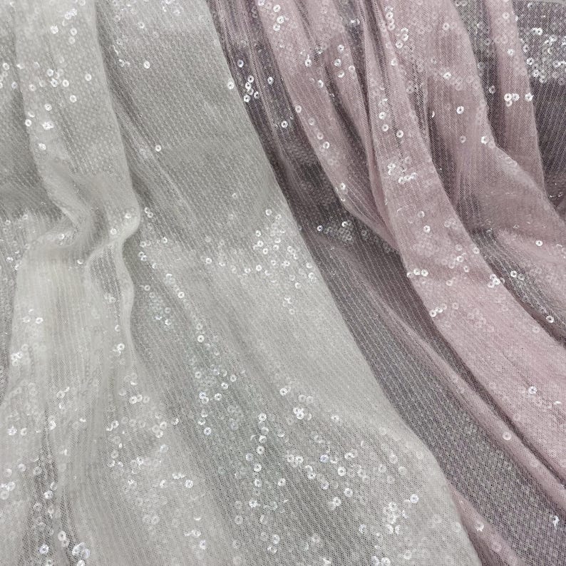 K&ouml;nnte beinhalten: Zwei St&uuml;cke durchsichtigen Stoffes mit Pailletten, ein wei&szlig;er und ein rosa, &uuml;bereinander gelegt.