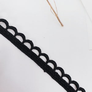 May include: Black lace trim with a scalloped edge.