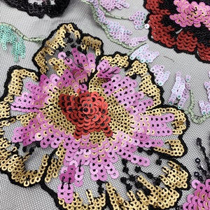 Puede incluir: Primer plano de una tela floral con lentejuelas rosas, doradas y rojas. La tela tiene un respaldo de malla negra.