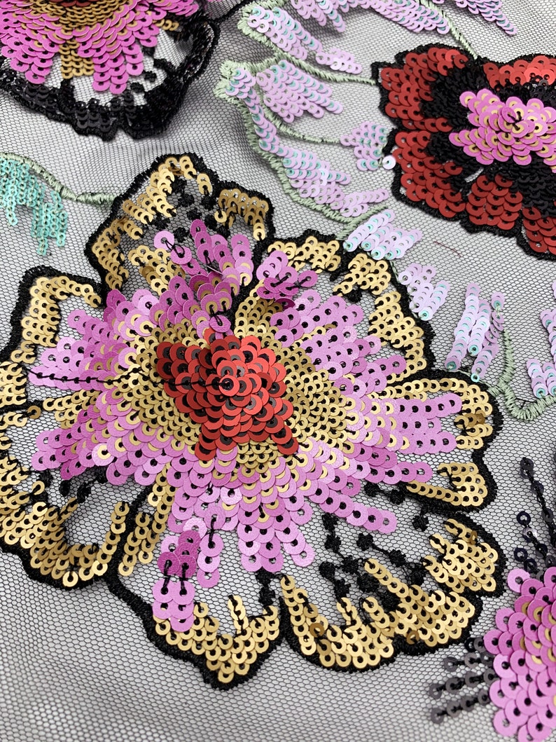 Puede incluir: Primer plano de una tela floral con lentejuelas rosas, doradas y rojas. La tela tiene un respaldo de malla negra.