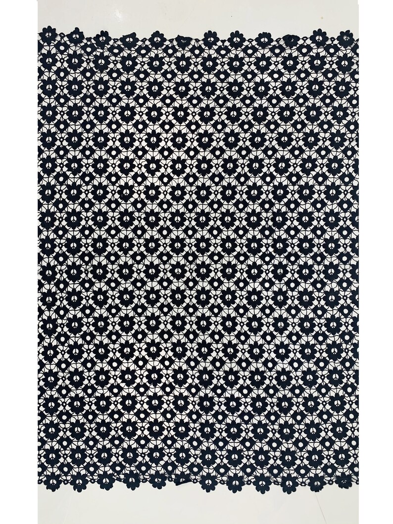 May include: Black lace fabric with a repeating pattern of small flowers. The fabric has a scalloped edge.