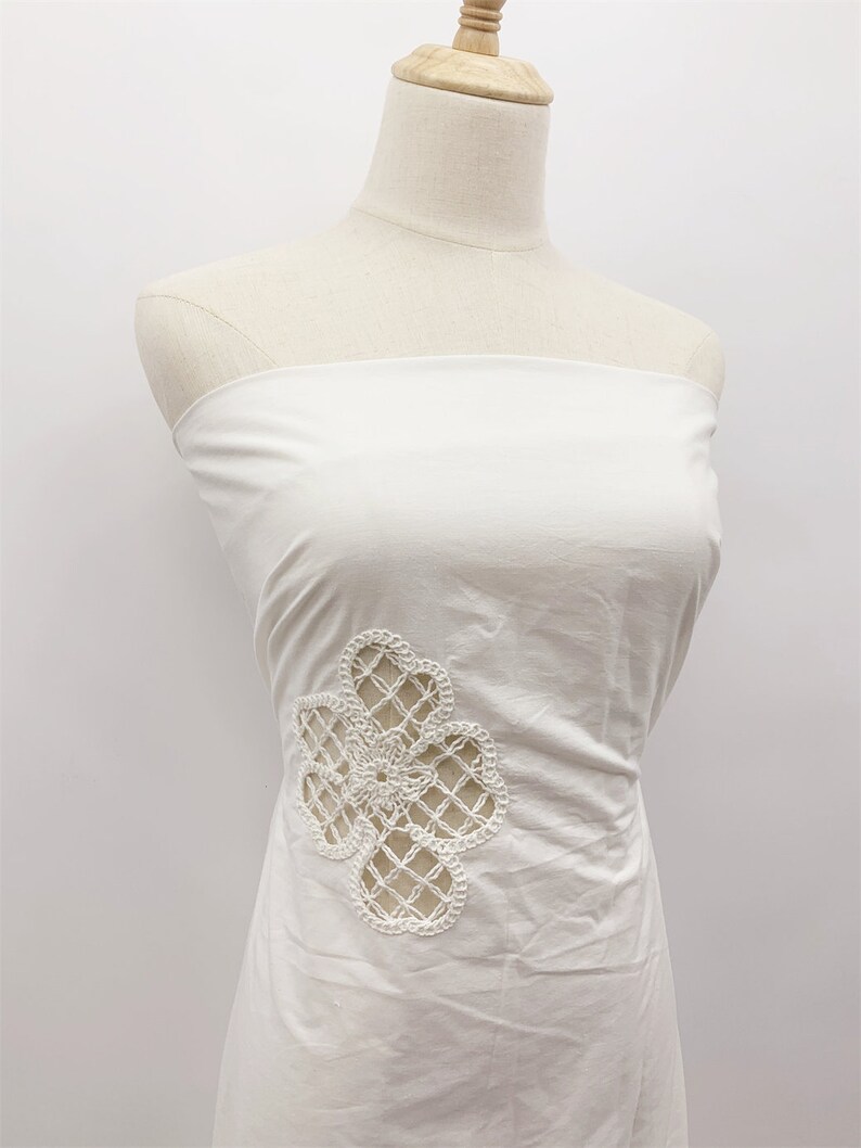Peut inclure: Robe blanche sans bretelles avec un motif de fleur en crochet d&eacute;licat sur le c&ocirc;t&eacute;.