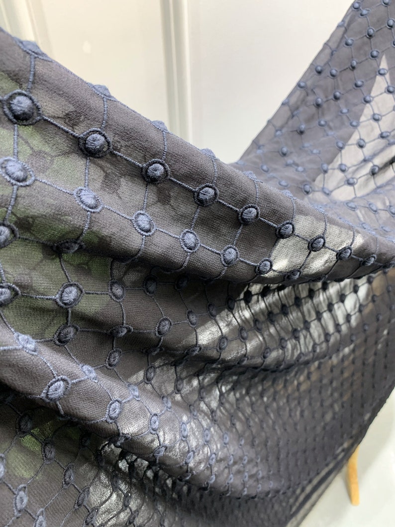 Puede incluir: Tela negra transparente con un delicado patr&oacute;n bordado de peque&ntilde;os c&iacute;rculos. La tela es suave y ligera, lo que la hace ideal para ropa o decoraci&oacute;n del hogar.