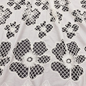Peut inclure: Tissu en coton blanc avec un motif de dentelle florale d&eacute;licate. La dentelle est d&eacute;coup&eacute;e en forme de fleurs et pr&eacute;sente un motif en forme de grille.
