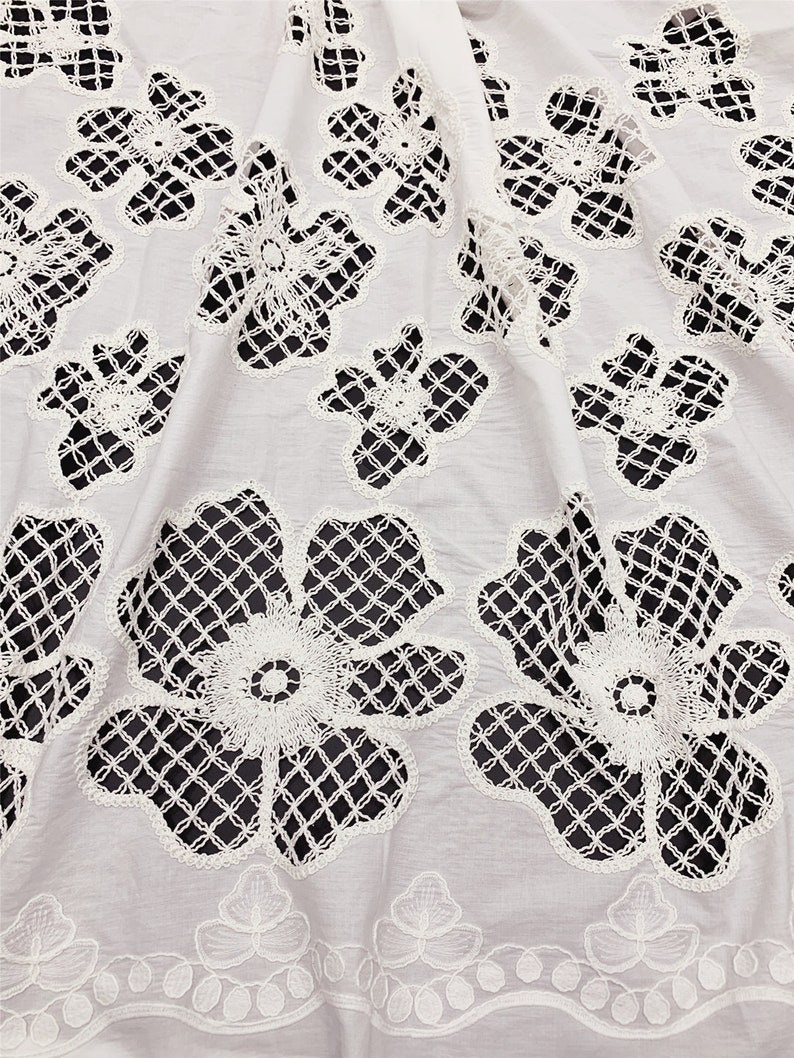 Peut inclure: Tissu en coton blanc avec un motif de dentelle florale d&eacute;licate. La dentelle est d&eacute;coup&eacute;e en forme de fleurs et pr&eacute;sente un motif en forme de grille.