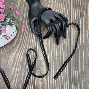 May include: Black elastic trim with a scalloped edge. The trim is approximately 1/2 inch wide.
