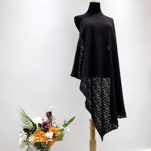May include: Black lace overlay dress with a one-shoulder design. The dress is asymmetrical and has a flowing silhouette.