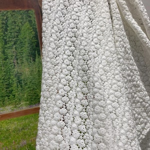 May include: White crochet fabric with a delicate floral pattern. The fabric is soft and airy, making it perfect for a variety of crafting projects.