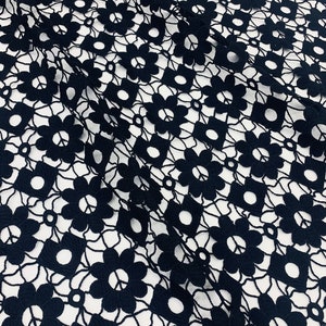 May include: Black lace fabric with a floral pattern. The fabric has a delicate, intricate design with small flowers and circles.