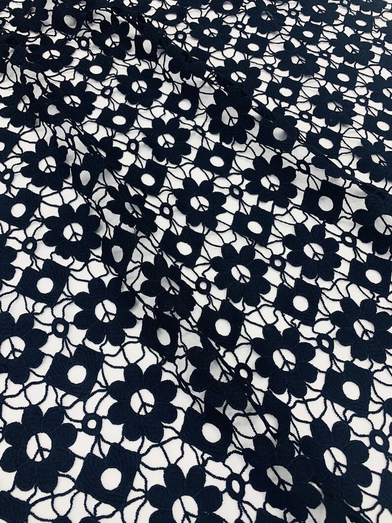 May include: Black lace fabric with a floral pattern. The fabric has a delicate, intricate design with small flowers and circles.