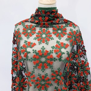May include: Red and green floral embroidered mesh fabric. The fabric has a repeating pattern of red hearts and green leaves.