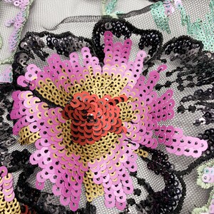 Puede incluir: Primer plano de una tela de malla negra con lentejuelas rosas, rojas y doradas formando un dise&ntilde;o floral.