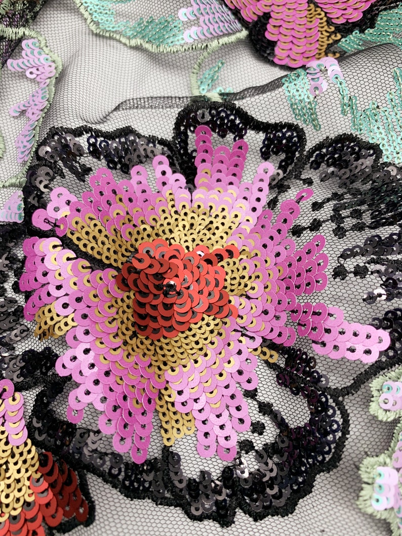Puede incluir: Primer plano de una tela de malla negra con lentejuelas rosas, rojas y doradas formando un dise&ntilde;o floral.