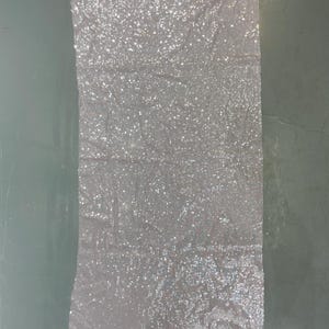 K&ouml;nnte beinhalten: Ein St&uuml;ck wei&szlig;er Stoff mit silbernen Pailletten. Der Stoff ist durchsichtig und hat eine weiche, flie&szlig;ende Textur.