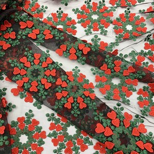 May include: Black mesh fabric with red and green embroidered hearts in a circular pattern.
