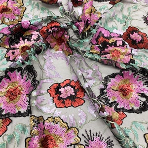 Puede incluir: Tela de malla negra con lentejuelas rosas, rojas y doradas bordadas en un patr&oacute;n floral.