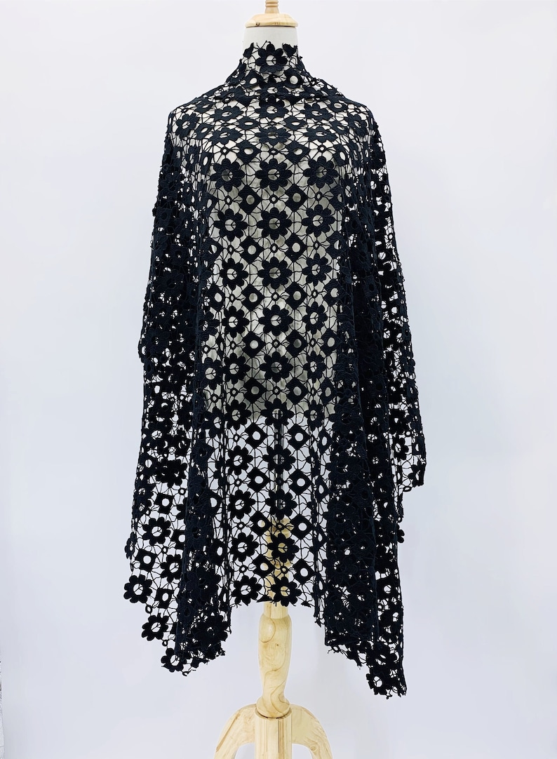 May include: Black crochet fabric with a floral pattern. The fabric is draped over a mannequin.