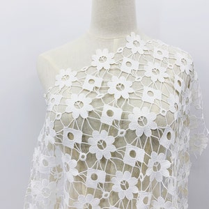 May include: White crochet fabric with a floral pattern. The fabric is delicate and has a square grid pattern with small flowers in each square.