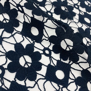 May include: Black lace fabric with a delicate floral pattern. The fabric is made of a fine mesh and has a soft, flowing texture.