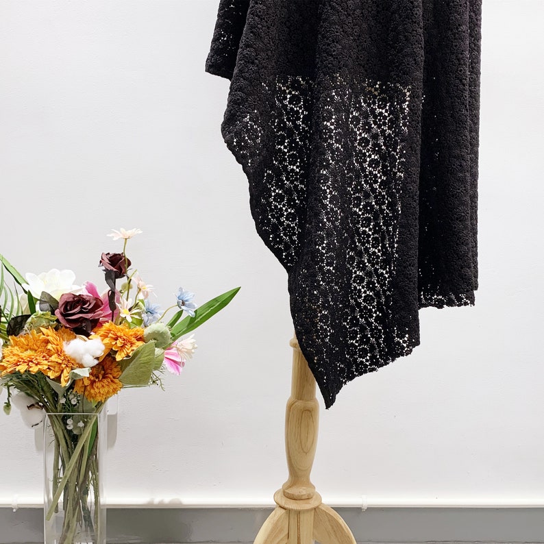 May include: Black lace maxi skirt with a floral pattern. The skirt is displayed on a wooden stand against a white background.