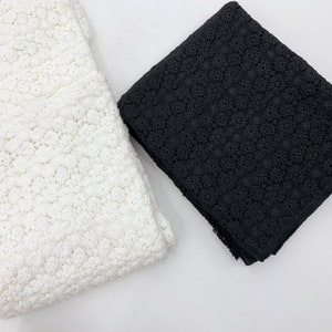 May include: Two pieces of lace fabric, one white and one black. Both fabrics have a delicate floral pattern.