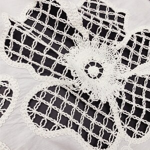 Peut inclure: Tissu en coton blanc avec une d&eacute;licate dentelle crochet&eacute;e blanche. La dentelle pr&eacute;sente un motif floral avec une texture en forme de grille.