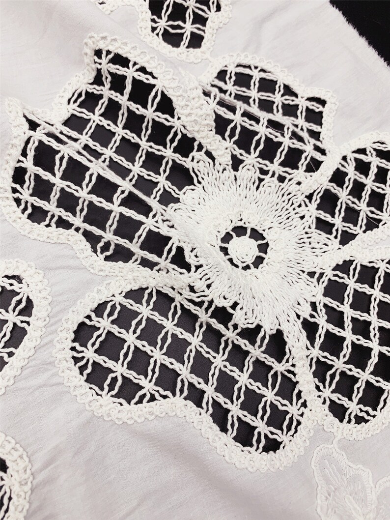 Peut inclure: Tissu en coton blanc avec une d&eacute;licate dentelle crochet&eacute;e blanche. La dentelle pr&eacute;sente un motif floral avec une texture en forme de grille.
