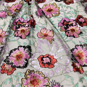 Puede incluir: Tela de malla negra con grandes bordados florales de color rosa, rojo y dorado. Las flores est&aacute;n adornadas con lentejuelas.