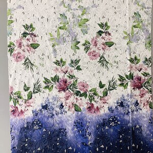 以下が含まれることがあります： ピンク、グリーン、ブルーの色の花柄がプリントされた白いレース生地。生地の下部はブルーのグラデーションになっています。