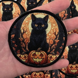 May include: A black cat with yellow eyes sits on a pile of jack-o'-lantern pumpkins. The cat is surrounded by fall leaves and vines. The background is a dark forest with a full moon.