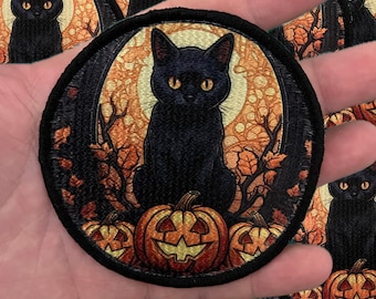 May include: A black cat with yellow eyes sits on a pile of jack-o'-lantern pumpkins. The cat is surrounded by fall leaves and vines. The background is a dark forest with a full moon.