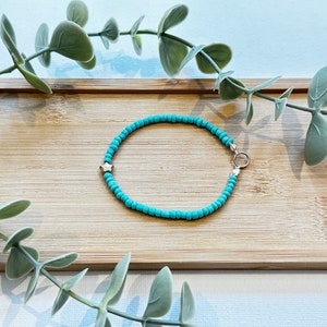 May include: A turquoise beaded bracelet with a gold star charm and a silver clasp.