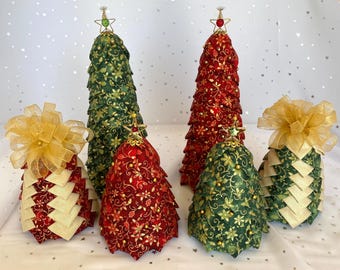 May include: A collection of handmade Christmas tree decorations in various sizes. The trees are made of fabric in red and green with gold floral patterns. Some trees have gold star toppers and gold ribbon bows. The background is white with a star pattern.