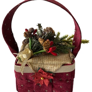 Pode incluir: Uma pequena cesta de Natal vermelha e dourada com al&ccedil;a. A cesta est&aacute; cheia de um ramo de pinho verde e marrom com bagas vermelhas e uma fita dourada.