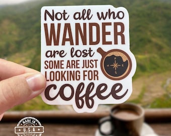 May include: A white sticker with the text "Not all who wander are lost, some are just looking for coffee" in brown. The sticker features a coffee cup graphic with a compass rose. A small "Made in U.S.A." emblem is also visible.