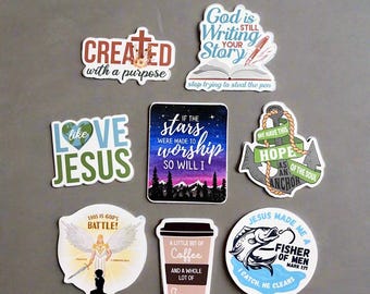 May include: A set of ten colorful stickers with Christian themes. The stickers feature phrases like "Created with a purpose", "Love like Jesus", "God is still writing your story", "If the stars were made to worship so will I", "We have this hope as an anchor of the soul", "This is God's battle", "A little bit of coffee and a whole lot of Jesus", and "Jesus made me a fisher of men".