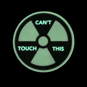 May include: A black and green glow-in-the-dark sticker with a radiation symbol and the text "CAN'T TOUCH THIS".