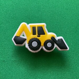 May include: Yellow toy construction vehicle with black wheels and a black scoop. The toy is made of plastic and has a white outline.