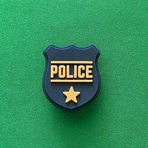 May include: A black and gold police badge with a star in the center. The badge is shaped like a shield and has the word "POLICE" written on it.