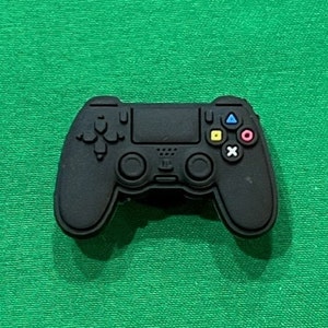 May include: A black plastic video game controller with colorful buttons. The controller has a black and white design with a textured surface.