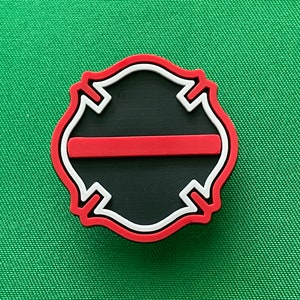 May include: A red, white, and black firefighter's badge with a thin red line across the center.