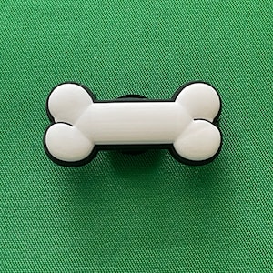 May include: White plastic dog bone charm with a black outline.