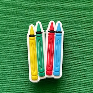 May include: Four colorful crayons in a white frame. The crayons are yellow, green, red, and blue.