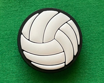 May include: A white volleyball with black stitching, on a green background.