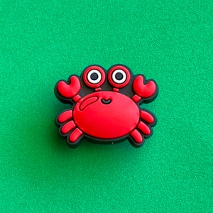 May include: Red and black cartoon crab charm with white eyes.