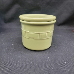 May include: A green ceramic butter dish with a lid. The dish has a woven pattern on the side.