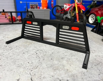 May include: Black metal truck bed rack with a slatted design and two red lights on the back.