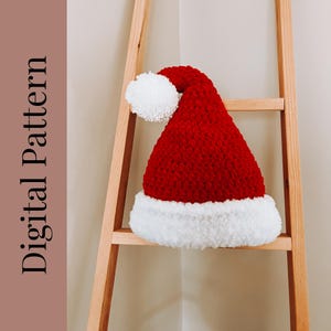 May include: A red and white crocheted Santa hat with a white pom-pom on top. The hat is sitting on a wooden ladder.